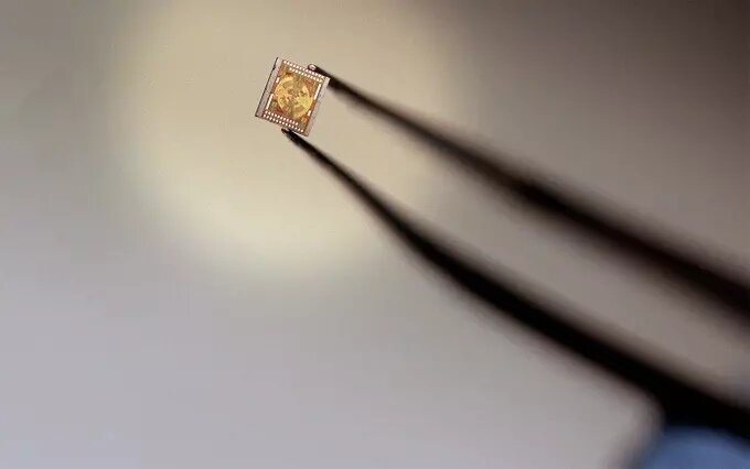 Исследователи из Осакского и Наньянского технологического университетов построили новый чип на основе фотонных топологических изоляторов, который позволит обеспечить передачу данных для сетей 6G. О своей работе ученые рассказали на страницах журнала Nature Photonics. 
Терагерцовые волны, или Т-лучи, располагаются в электромагнитном спектре между инфракрасным и микроволновым излучением. Они обладают высокой частотой и в перспективе могут использоваться для передачи информации в сетях следующих поколений. Однако прежде чем использовать этот вид излучения в телекоммуникациях, необходимо решить фундаментальные проблемы. Самые большие из них — это дефекты материала и частые ошибки в передаче информации, которые наблюдаются в обычных волноводах, таких как кристаллы или полые кабели.

Эти проблемы можно преодолеть с помощью фотонных топологических изоляторов, в которых световые волны проходят по поверхности и краям материала. Когда свет движется вдоль них, его можно перенаправить для огибания острых углов, и тогда его поток будет сопротивляться нарушению несовершенств материала.

Авторы нового исследования создали небольшой кремниевый чип с рядами треугольных отверстий, которые, направлены в противоположных друг относительно друга направлениях. При движении по такому чипу световые волны становятся топологически защищенными. Ученые показали, что такой чип может передавать сигналы без ошибок, направляя терагерцовые волны вокруг 10 острых углов со скоростью 11 гигабит в секунду, минуя любые материальные дефекты, которые могли возникнуть на этапе производства кремния.

Открытие исследователей позволит создать в будущем терагерцовые интерконнекторы — структуры, которые соединяют различные компоненты в цепи. Их можно интегрировать в устройства беспроводной связи следующего поколения.

Согласно расчетам, сети 6G позволят передавать данные со скоростью в несколько терабайт в секунду.