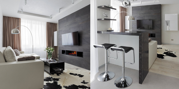 Обыграть электрокамин в интерьере минимализм хорошо бытовой техникой и мебелью. Картину заменяет телевизор, цвет и форму очага повторяют встроенные полки для ПДУ, а облицовка портала перекликается с отделкой барной стойки.