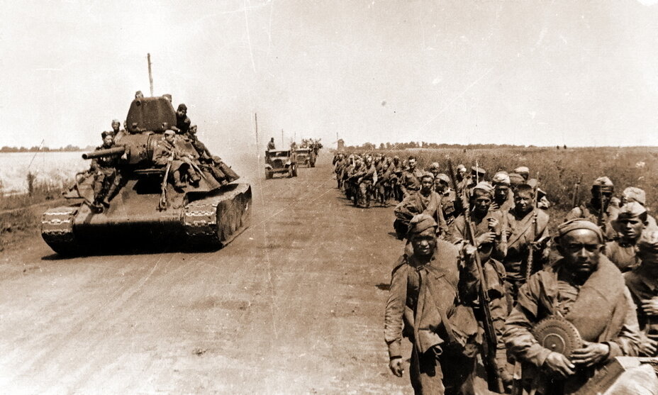 Советская пехота пылит в сторону фронта по грейдерной дороге. Тем, кто проделывает свой путь на броне или в кузове грузовика, повезло больше. Курская дуга, лето 1943 года