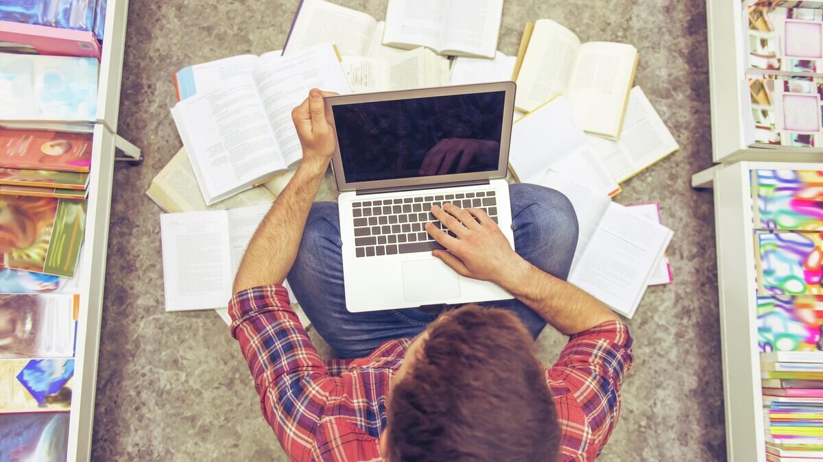    Студент с ноутбуком в библиотеке© Depositphotos / GeorgeRudy