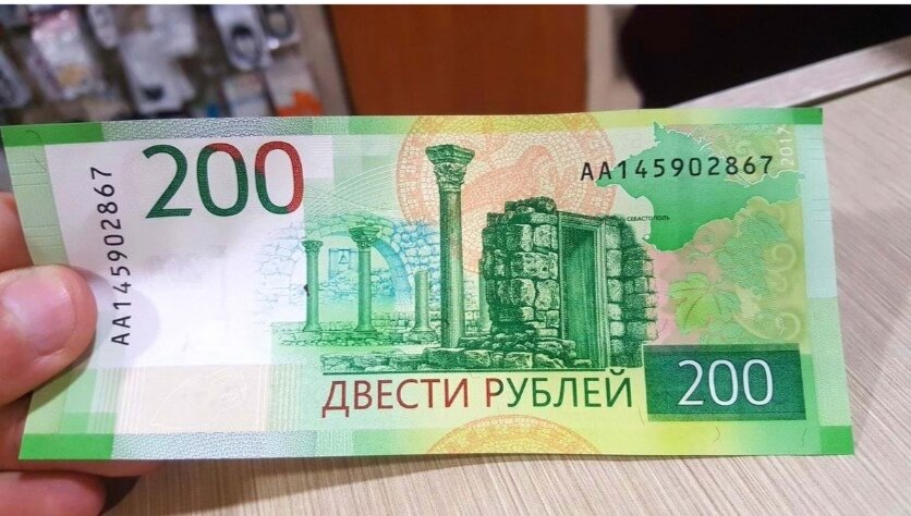 Вот уже как более чем 20 лет в обороте на российский территории находятся привычные всем рублевые деньги, а доступны такие в различных самых разных номиналах. Именно в рублях жители России при нахождении внутри страны обязаны что-либо оплачивать, если речь идет о товарах и услугах, потому что любые другие валюты в стране считаются второстепенными, то есть их можно иметь, но перед оплатой чего-либо с их помощью придется сначала произвести обмен на местные деньги, а только затем оплачивать желаемые товары и услуги. Многие годы в обороте находились банкноты номиналов 10 рублей (больше не выпускаются), 50 рублей, 100 рублей, 500 рублей, 1000 рублей и 5000 рублей, все из которых гарантированно попадали в руки каждому россиянину. Тем не менее, в 2017 году российские власти решили разнообразить жизнь всех россиян, а потребовалось для этого создать совершенно новые банкноты рублевого типа, но номиналов 200 рублей и 2000 рублей. Они крайне сильно отличаются по части внешнего вида от денежных единиц образца 1997 года, причем это касается не только их внешнего вида, но еще и размеров. Новые купюры имеют три степени защиты, поэтому до сих пор, даже спустя почти три года, их до сих пор никто так и не сумел подделать, к большому счастью для жителей страны. Первое время многие люди с большим недоверием относились к таким деньгам, однако затем, спустя какое-то время, ситуация в этом плане в полной мере нормализовалась.Теперь подобные денежные единицы уже совершенно не вызывают ни у кого никаких вопросов, то есть к таким все в полной мере привыкли. Впрочем, лишь единицы знают о том, что существуют редкие купюры, которые, даже не смотря на свой объявленный номинал, обладают гораздо большей ценностью. Не так давно одному из жителей России в руки попала крайне редкая банкнота номинала 200 рублей, которую он случайно обнаружил. Эта самая купюра обладает всеми двойками в своем персональном девятизначном номере, кроме трех последних цифр. В итоге, последние четыре цифры имеют сочетание «2017», что соответствует году запуска такой денежной единицы в оборот на российской территории, а это придает ей огромную ценность. Внимательный россиянин, который и обнаружил такую банкноту, посчитал необходимым выставить ее на продажу на одном из популярных аукционов среди коллекционеров, и удача не заставила себя долго ждать. Уже спустя менее чем двое суток нашелся покупатель, который согласился купить такую денежную единицу за целых 200 тысяч рублей, то есть за громадную сумму денег. Покупатель согласился на это предложение и тем самым реализовал полученную на сдачу банкноту 2017 года в целых 1 000 раз дороже ее реального номинала, а ведь не заметь он редкого сочетания цифр, все могло случиться иначе. Именно поэтому следует хотя бы иногда осматривать полученные на сдачу деньги. Если у таких будут редкие сочетания цифр, за них, возможно, удастся выручить даже еще больше денежных средств.