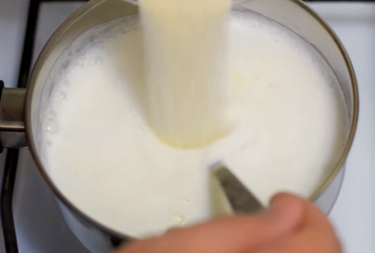 Как только молоко закипело, убавляем огонь на минимум. В молоко добавляем манную крупу небольшими порциями и в это время тщательно перемешиваем. Засыпать крупу нужно равномерно, в этом случае каша будет без комочков.