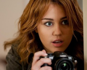 Агент под прикрытием. Но фотоаппарат ее выдает. И вообще, 21 век, "гугл гласс" лучше всего использовать :)