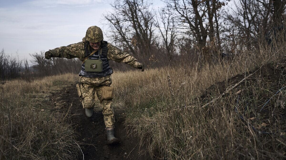    Украинский солдат бежит в укрытие на линии соприкосновения возле Марьинки© AP Photo / Libkos