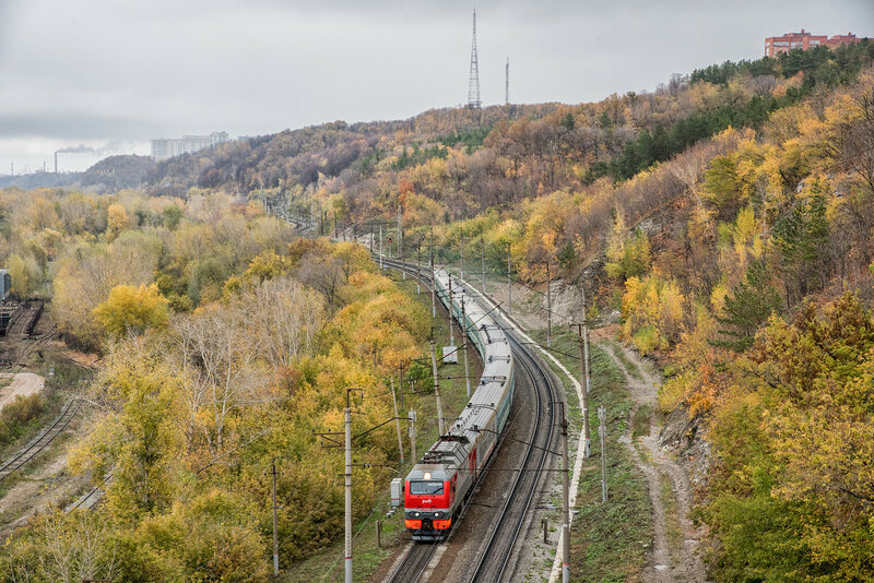 Первый поезд - ЭП2К с поездом Казахстанских железных дорог в Москву. Слева вдали - нефтеперерабатывающие заводы, по центру - мачта цифрового ТВ.