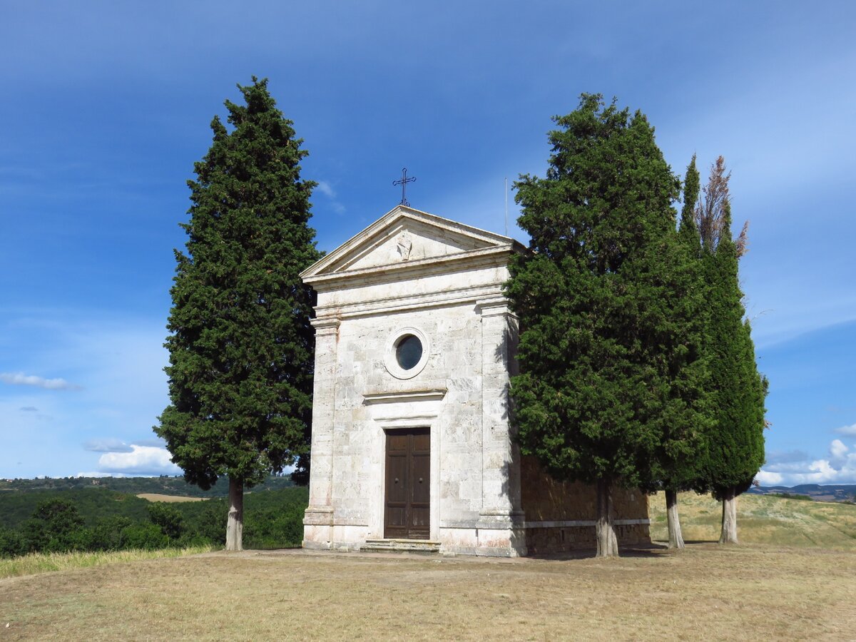 Простой, но очень элегантный фасад Часовни с небольшим окошком-розеткой и дворянским гербом на фронтоне (фото автора)
