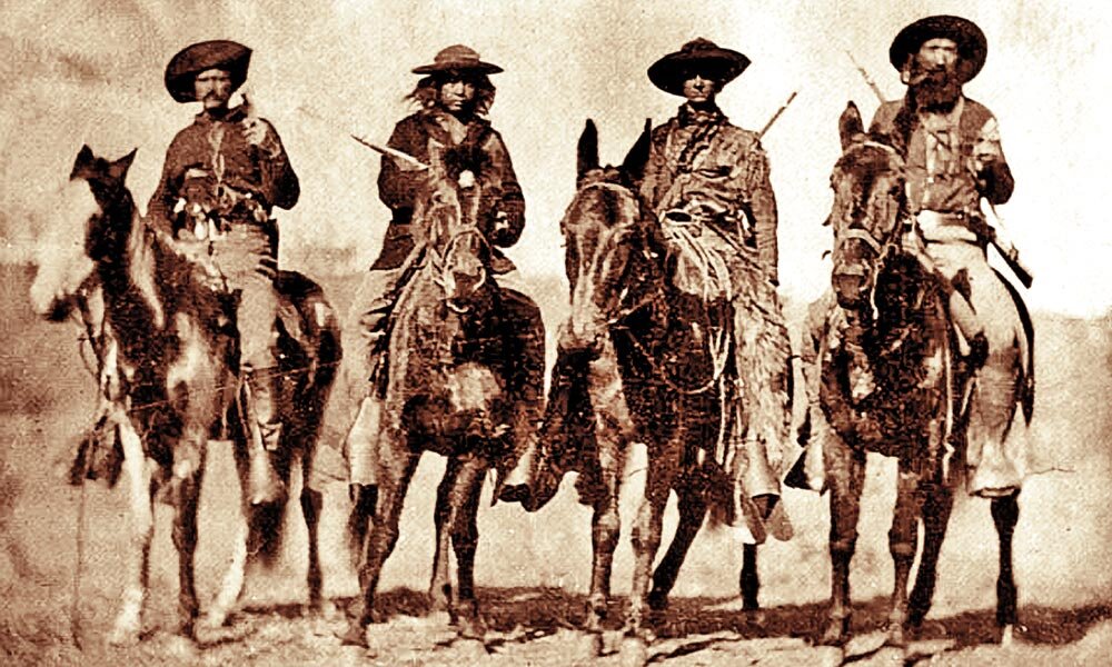 Разведчики Джорджа Кастера - (слева направо) Билл Комсток, Эд Герье, Томас Адкинс и Мозес «Калифорнийский Джо» Милнер - запечатлены верхом на лошадях и мулах (два справа) на фотографии, сделанной, вероятно, в 1867 году во время кампании генерал-майора Уинфилда Скотта Хэнкока в Канзасе.