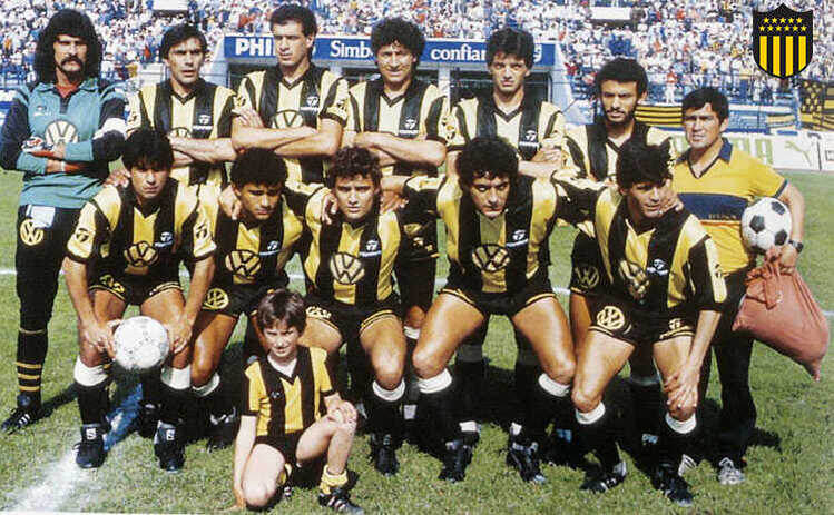 "Пеньяроль": лучший клуб Южной Америки ХХ века "Пеньяроль", базирующийся в столице Уругвая Монтевидео, был основан в 1891 году как железнодорожный крикетный клуб. Клуб на протяжении всей своей истории был мультиспортивным, а футбол до 1913 года был одной из секций организации. На данный момент "Пеньяроль" является самым успешным футбольным клубом Уругвая, но их принципиальный соперник "Насьональ" время от времени требует лишить "ауринегрос" пяти чемпионских титулов, добытых до 1913 года. Но это так - лишь бы поговорить и повозмущаться в попытке доказать свое превосходство над главным антагонистом и свою исключительность.Что бы там ни говорили, а именно "Пеньяроль" в сентябре 2009 года был назван Международной федерацией футбольной истории и статистики (IFFHS) лучшим клубом Южной Америки ХХ века. Долгое время "Угольщики" (одно из прозвищ "Пеньяроля") удерживали лидерство в клубном рейтинге КОНМЕБОЛ. 14 игроков "Пеньяроля" в составе сборной Уругвая становились чемпионами мира. Основу "Чарруас" на ЧМ-1950, завершившимся их победой, составили игроки именно этого клуба. 1987 год. "Пеньяроль" - победитель Копа Либертадорес Что же касается достижений "Угольщиков", то в их активе 52 чемпионских титула уругвайской Примеры. Правда, чемпионства 1924 и 1926 годов Ассоциация футбола Уругвая (АУФ) не признает. Первый по причине того, что турнир прошел под эгидой Федерации футбола Уругвая, а не АУФ, второй же чемпионат не признается полностью официальным. Впрочем, 50 чемпионств все равно являются рекордом Уругвая. Также "Пеньяроль" 12 раз выиграл Лигилью, специфический уругвайский турнир, который можно сравнить с имеющимися в некоторых странах Европы Кубками лиги. Также "ауринегрос" являются самым успешным уругвайским клубом на международной арене. "Пеньяроль" пять раз (третий показатель в Южной Америке) выигрывал Копа Либертадорес и трижды – Межконтинентальный кубок (причем уругвайцы первыми добились этого показателя, являющегося рекордом). Источник: https://www.footboom.com/foreign/newscommon/1587234762-top-10-samykh-titulovannykh-futbolnykh-klubov-mira-ot-urugvaya-do-yegipta.html