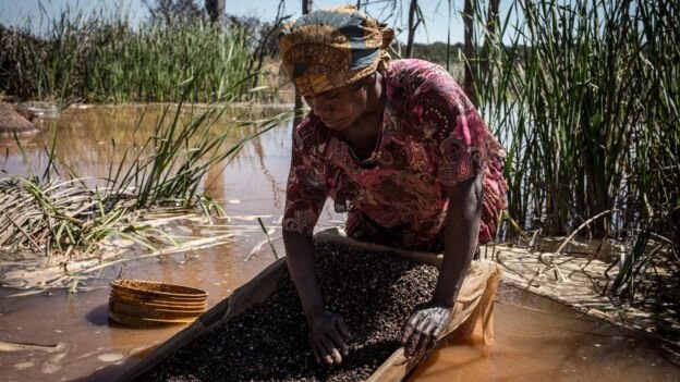Женщина отделяет кобальт от грязи и скал вблизи шахты в Демократической Республике Конго