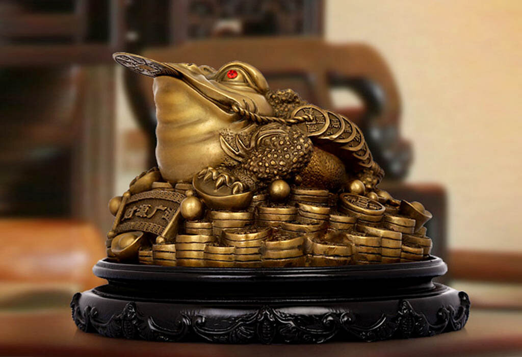 Трехлапая жаба по фен-шуй символизирует источник богатства. По-другому и быть не может, ведь традиционно фигурка лягушки восседает на горе монеток. Также жабка держит монетку во рту. При покупке такого амулета нужно разобраться во всех тонкостях его использования. Сегодня мы этим и займемся.