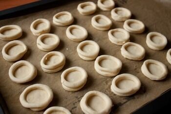     На доске с помощью скалки раскатываем тесто в одном направлении, слегка присыпав его мукой.       Выемкой (стаканом) деаметром 4 см на нашем тесте делаем кружки. Выемкой поменьше ( диаметр 3-3.5) вырезаем из этих кружков кольца. У яйца отделить белок и немного его взбить миксером в удобной для вас посуде.    