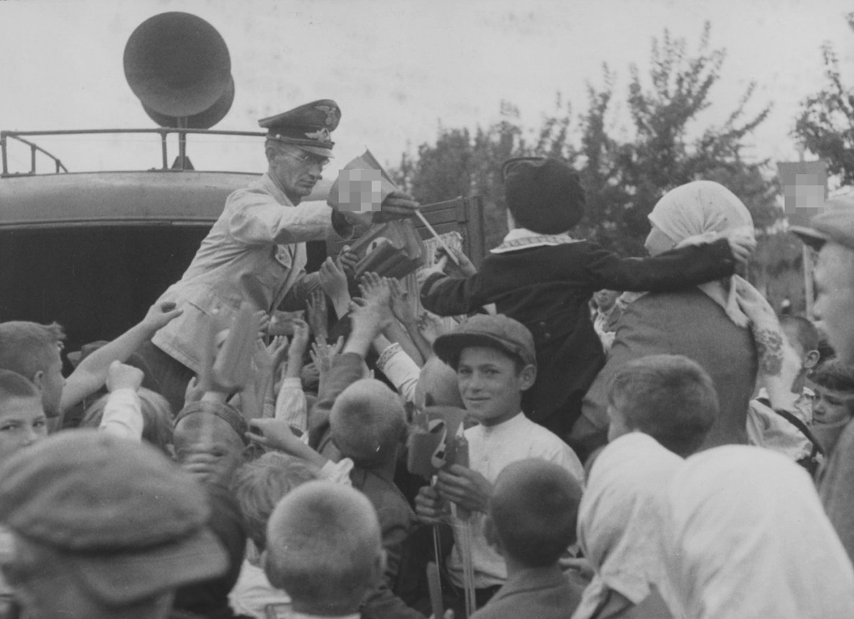 Сотрудник рейхсминистерства оккупированных восточных территорий раздает флажки со свастикой жителям Киева во время празднования второй годовщины захвата города немецкими войсками, 19 сентября 1943 года / waralbum.ru