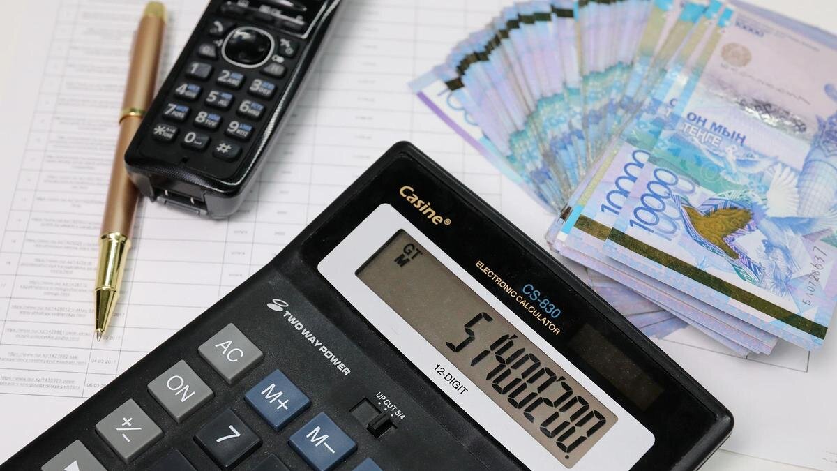    Калькулятор и деньги лежат на графике:NUR.KZ / Петр Карандашов