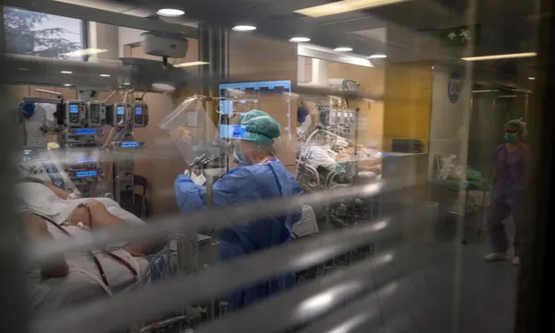 Больничные работники оказывают помощь пациенту в больнице Vall d'Hebron в Барселоне. Испания зафиксировала самое большое число смертей от Covid-19 после Италии. 
