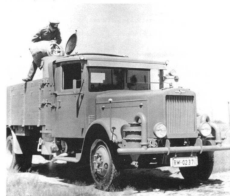 Буквы RW на номере этого грузовика означают, что он принадлежит Рейхсверу. Т.е сделан до 1933 года. По всей видимости некоторое количество автомобилей с газогенераторами уже имелось в немецкой армии еще и до 1933 года. Военный засыпает в генератор топливо, что он там засыпает — понять сложно. Возможно, что дрова или....шишки.