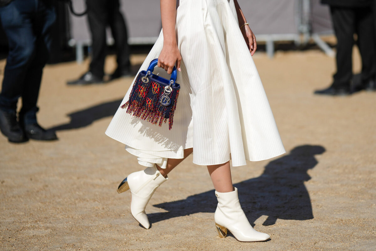    PARIS, FRANCE - SEPTEMBER 27: A guest wears a white striped print pattern shirt / short sleeves / midi long dress from Dior, a black shiny leather mesh / fishnet large belt from Dior, white shiny leather pointed ankle boots, a blue shiny leather with embroidered red / orange / yellow fringed pearls Lady D-Light handbag from Dior, outside Dior, during Paris Fashion Week - Womenswear Spring/Summer 2023, on September 27, 2022 in Paris, France. (Photo by Edward Berthelot/Getty Images) Наталья Степанова