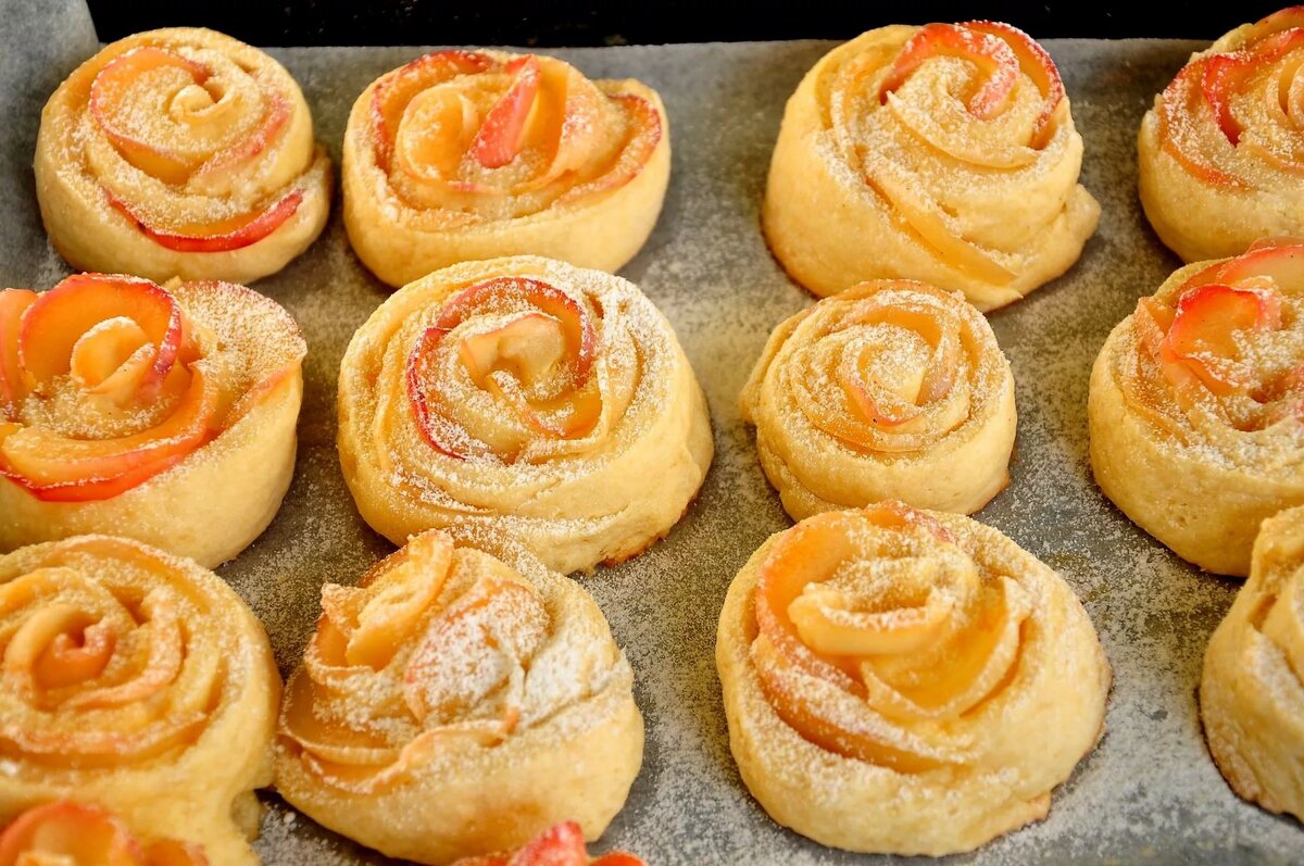 Это красивая и вкусная выпечка. 
Ингредиенты:

-Молоко — 250 мл
-Яйца (2 в тесто, 1 в начинку) — 3 шт
-Сахар (100 г в тесто, 100 г в начинку) — 200 г
-Слив. масло (или маргарин) — 100 г
-Мука (приблизительно) — 600-700 г
-Ванильный сахар (1 пакетик в тесто,1 в творог) — 2 пакет.
-Дрожжи (свежие или сухие 2 ч.л.) — 25 г
-Творог — 500 г
-Изюм — 100-150 г
-Цедра лимона (по желанию, в тесто)
-Соль (неполная) — 1 ч. л.

Приготовление:

Первым делом зальем изюм кипятком
Теперь делаем опару.
Подогреем молоко, перельем в миску.
Добавим в молоко дрожжи ...сахар ...и примерно половину муки (лучше стакан, чтобы опара не была такая густая) 
Размешаем и поставим в теплое место подходить
Готовим сдобу:
Растопим масло, немного остудим
Добавим в масло яйца ...сахар ...ванилин ...соль. Перемешаем.
Опара подошла.
Добавляем в опару сдобу
Перемешиваем
Понемногу добавляем оставшуюся муку ...и вымешиваем довольно таки крутое тесто.
Ставим его в теплое место для подъема
Готовим начинку:
В творог (обязательно комнатной температуры) добавляем яйцо (таааак... а где же яйцо... кажется, я его забыла добавить...)
...ванильный сахар ...сахар (100 г) и изюм (слить воду через сито)
Все хорошо размешиваем (если творог жидковат, можно добавить муки или манки)
Тесто подошло
Из подошедшего теста делаем, примерно, 24 одинаковых шарика, и оставляем их немного подойти.
Лепешку раскатываем, делаем 3 разреза так, чтобы части были немного разные, одна часть чуть больше другой
Кладем в середину начинку
Одну из трёх частей (самую маленькую) оборачиваем вокруг творога и скрепляем.
Затем делаем то же самое с частью побольше.
И последней оборачиваем самую большую часть лепёшки.
Место скрепления должно быть как можно ниже, у основания булочек, иначе они будут падать.
Соединяем как можно крепче,особенно последнюю часть.
"Розочка" готова
Даем булочкам хорошо подойти 
В желток добавить немного молока
Размешать и смазать булочки
Выпекаем при температуре 180 С