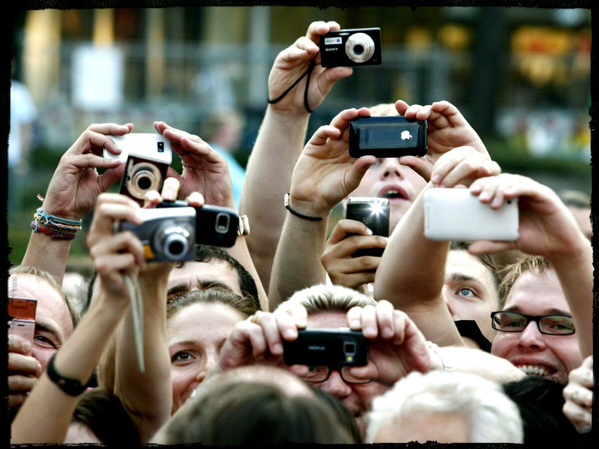 Фотографировать мероприятие. Фоткает на телефон. Толпа людей фоткает. Человек фоткает на телефон. Много людей фоткают.