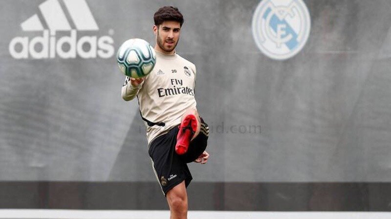 Первая неделя тренировок «Мадрида» перед рестартом сезона подтвердила, что Марко Асенсио вернулся в строй – тренерский штаб приятно удивлен физической формой своего игрока, который уже занимается в том же режиме, что и его партнеры по команде. Все это, в свою очередь, открывает новые возможности для Зинедина Зидана, который видит Асенсио в роли «девятки» в случае травмы Карима Бензема или других непредвиденных обстоятельств.   
Статистика выступлений Асенсио говорит сама за себя: в сезоне 2016/17 он являлся шестым бомбардиром команды (10 голов), несмотря на то, что по количеству сыгранных минут он был всего лишь 17-м. В следующем сезоне игрок занял уже четвертую строчку в списке бомбардиров (11 голов) – его опережали только Роналду, Бэйл и Бензема, однако по количеству проведенных минут на поле он был только 13-м. Руководствуясь данной статистикой и опытом предыдущих лет, Зидан был уверен, что без Роналду в составе Асенсио способен играть ключевую роль и забивать более 20 голов за сезон. 
 
Полузащитник чувствует себя весьма комфортно, играя на правом фланге, однако, если предоставить ему свободу, он также может проявить себя и на позиции «ложной девятки», как это случилось в матче против «Ювентуса» в рамках предсезонной подготовки времен Хулена Лопетеги. В той встрече Асенсио был «ложной девяткой» всего 45 минут, но за это время он успел отличиться двумя забитыми мячами. 
 
Лопетеги также использовал Асенсио в качестве «ложной девятки», будучи тренером сборной Испании. Самой яркой победой «Красной фурии» Лопетеги стал матч, в котором испанский специалист выпустил Асенсио «ложным нападающим» – речь идет о победе 3-0 над сборной Италии на «Сантьяго Бернабеу». 
 
Затем, в сентябре 2018, случился разгром сборной Хорватии со счетом 6-1, но уже под руководством Луиса Энрике. В том матче Родриго был нападающим, но он часто менялся позицией с Асенсио, который занимал правый фланг. Тогда Марко забил гол и отдал три голевые передачи. 
 
Очевидно, что Зидан не рассчитывает на Мариано Диаса (65 сыгранных минут в текущем сезоне) и травмированного Луку Йовича, который не оправдал ожиданий (2 гола). Тем не менее универсальность Асенсио позволяет главному тренеру «Мадрида» разнообразить игру в атаке: при схеме 4-3-3 испанец может сыграть как на фланге (желательно правом), так и в роли «ложной девятки» при отсутствии Бензема. Более того, при схеме 4-4-2 Асенсио может выступить в качестве нападающего в паре с Бензема или даже Азаром. 
 
Вернувшись в «Мадрид», Зидан ожидал увидеть, что после ухода Роналду остальные игроки атаки сделали шаг вперед для того, чтобы команда не чувствовала себя зависимой от прежней россыпи голов португальца. Однако только Бензема справился с этой задачей. Так, в сезоне 2017/18 француз забил 12 голов в течение 3237 минут (в среднем один гол каждые 269 минут), но по возвращении в Королевский клуб Зидан обнаружил новую версию своего нападающего: 19 голов за 2957 минут (один гол каждые 155 минут). Тем не менее остальные игроки группы атаки не поддержали инициативу Бензема. Девятый номер «Мадрида» является лучшим нападающим команды, а второе место занимает Серхио Рамос, на счету которого семь голов, четыре из которых были забиты с пенальти. Ровно столько же забил и потерявший доверие главного тренера Родриго Гоэс, следом за которым с пятью забитыми мячами расположились два полузащитника: Тони Кроос и Лука Модрич.