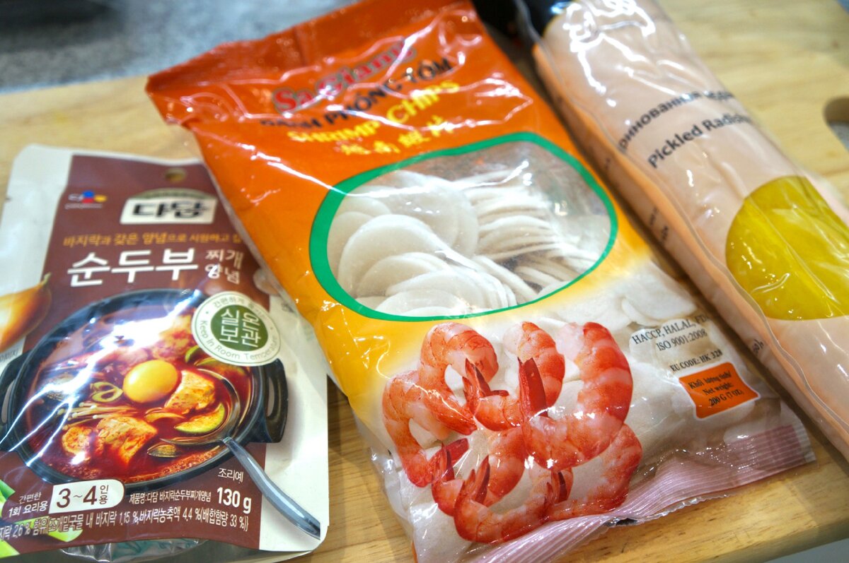 Заправка и чипсы достались мне в подарок, а вот редьку пришлось заказать самой. Но без нее мой замысел бы не удался! Вот, что нам понадобится:                                                                                           Креветочные чипсы — 100 гр, заправка — 1 пачка, маринованная редька — по вкусу,
кунжутное масло — 1 ст.л, свинина — 500 гр, чеснок — 2 зубчика, красный лук — 2 шт.,
морковь — 1 крупная, лук-порей — 2 стебля (только белая часть),  пекинская капуста — треть качана, имбирь — пара см, зеленый лук — пучок, осьминожки в соку — 1 пачка