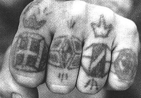  Тюремные татуировки – это особые метки, которые могут многое рассказать об их владельце: о его положении в неформальной иерархии заключенных, о статье, по которой он отбывает наказание, и прочее. И если некоторые наколки достаточно безобидны, то за другие зеку приходится отвечать. Все настолько серьезно, что порой на кону может стоять жизнь. За наколку ответишь Когда осужденный попадает на зону, то объектом внимания его новых сокамерников становятся его татуировки. В тюрьме просто так наколки никто не набивает, за их наличие принято отвечать. Если зек сделал себе определенную смысловую татуировку, на обладание которой он в реальности не имеет никаких прав, то ему придется за решеткой крайне несладко. Наказание не заставит себя ждать: могут удалить наколку вместе с кожей, избить или даже прикончить ее обладателя. В целом тюремные татуировки делятся на несколько типов, по степени «престижа». Самая представительная – так называемая регалка, имеется только у элиты криминального мира, прежде всего у воров в законе. Рангом ниже находятся портачки, а самые позорные наколки – нахалки. Последние преимущественно делаются насильно в качестве наказания за серьезные косяки. Перстни Подобная дифференциация очень хорошо заметна на татуировках-перстнях, наносимых на фаланги пальцев. Такие наколки представляют собой сочетание точек, условных символов и линий. Среди них есть как почетные, так и нейтральные и презираемые. Самый "косячный перстень" 