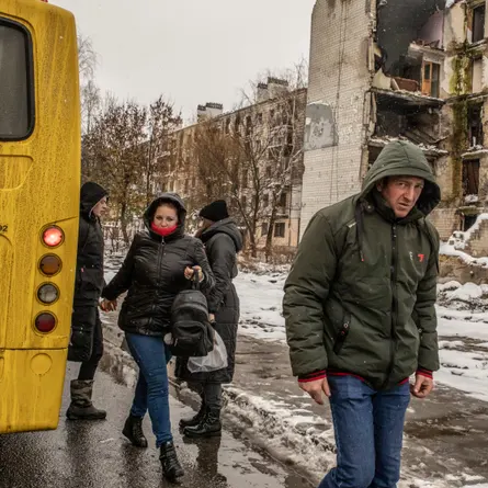 Жители Бородянки выходят из автобуса на улице, сильно разбомбленной во время весенних боёв.