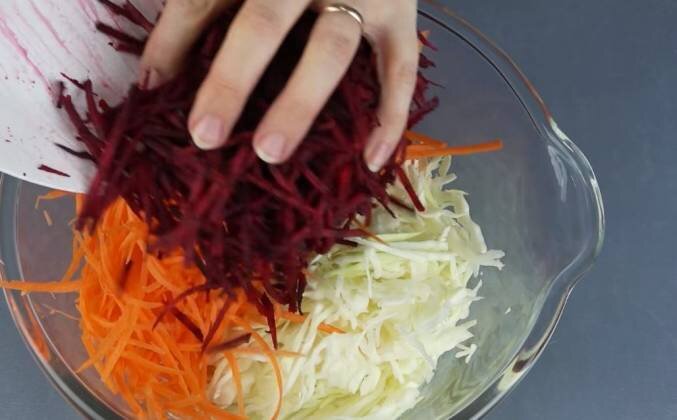 1. Шинкуем капусту мелко, натираем на терке морковку свежую очищенную морковку. Добавляем в миску тертую свеклу. Перемешиваем овощи руками, чтобы пустить сок.