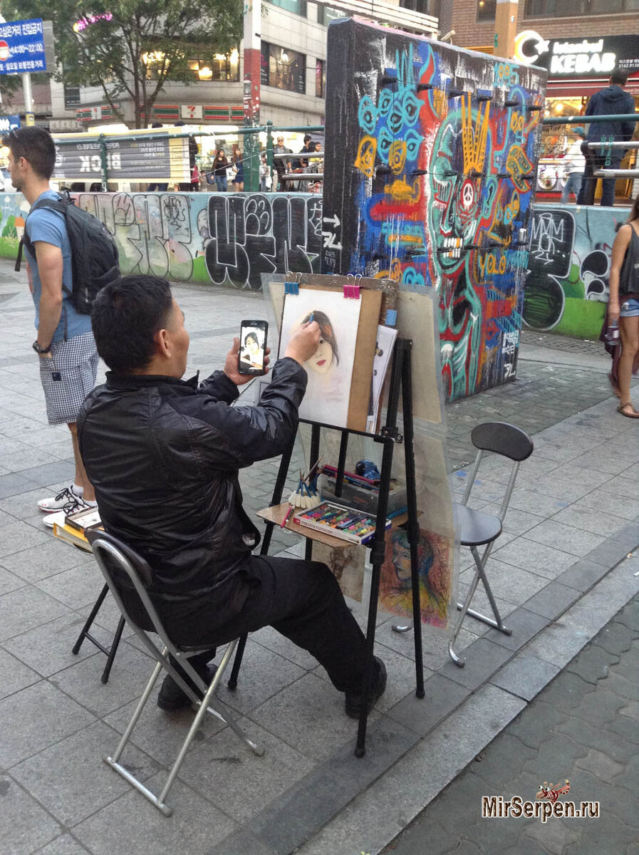 Уличный художник по заказу влюбленного молодого человека рисует портрет его девушки