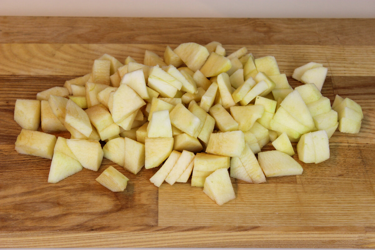 Яблоки для шарлотки помыть, обсушить, срезать яблочную кожуру, разрезать на 4 части, вырезать сердцевину, нарезать на дольки, затем на средние кубики. 