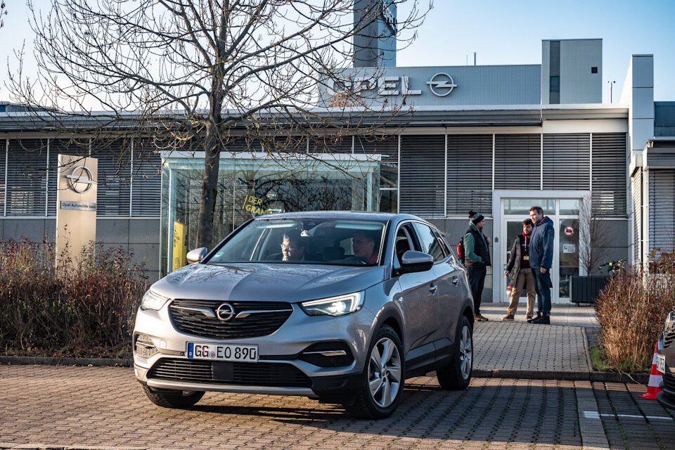  Opel Grandland X на фоне проходной завода в Айзенахе