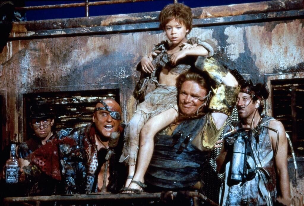 Циничный правитель рассказывает про прогресс и землю будущего. Потом кидает толпе горсть сигарет и заставляет всех работать на непонятную ему самому идею. Фильм Водный мир.