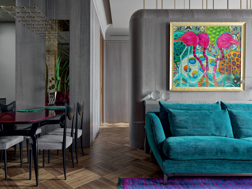 Округлые карнизы рифмуются с формой перегородки между гостиной и спальней. Латунные крепления перегородки расположены хаотично и имеют разный диаметр, перекликаясь с дизайном светильников в зоне гостиной. За диваном имеется консоль с нишей для журналов. Картина написана Лейлой Кравцовой на заказ.