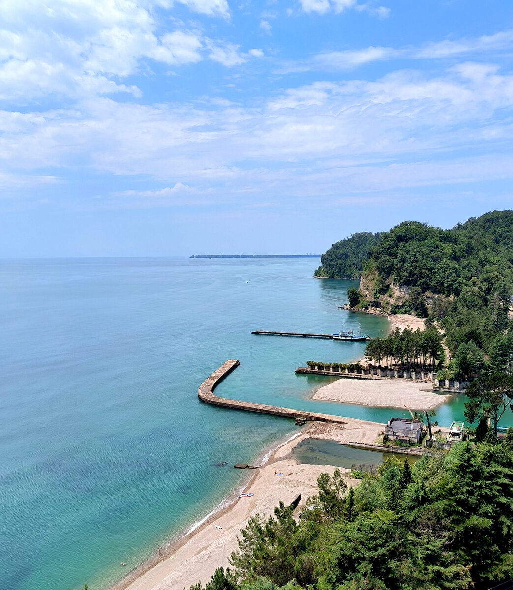 Вид с балкона 12 этажа в сторону Пицунды, на пирс и пляж дачи Горбачёва. В обеих отелях главным достоинством является прекрасный вид с балконов номеров на море или горы. Берег порос соснами, отсюда неповторимый аромат.  