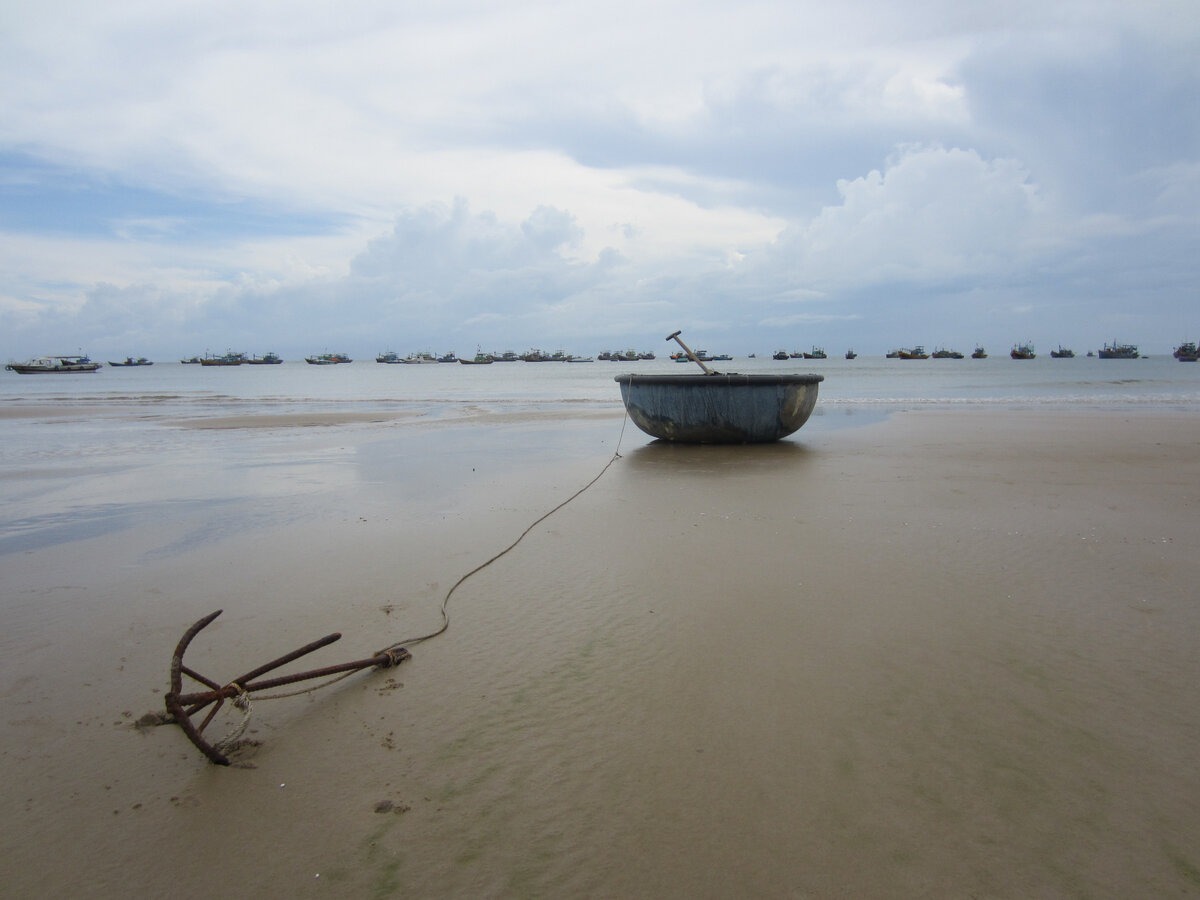 Лодка-тазик, весло, якорь. На дальнем плане рыбацкая флотилия