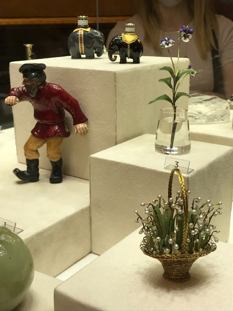 Слева "Пляшущий мужик", вдалеке слоны из дымчатого кварца, ближе анютины глазки, на переднем плане корзинка с ландышами.