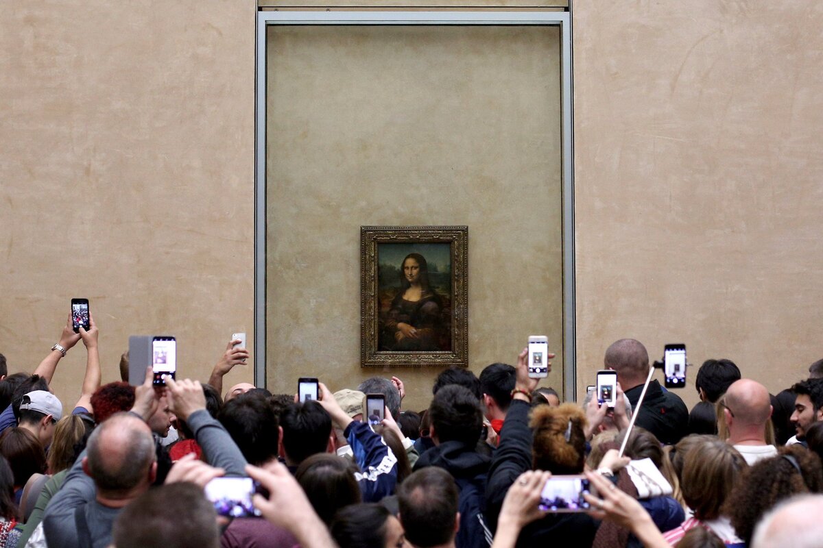 Обычная картина топящихся туристов напротив «Моны Лизы» на ее обычном месте в Большой галерее Лувра. Источник иллюстрации: Викимедиа
