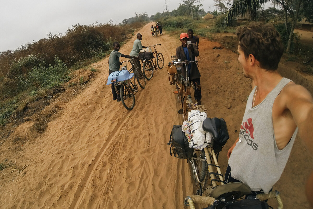 Истории путешествий

 Переключить навигацию

 Малярия в Конго

 Неудачная остановка на пути в Киншасу

 АРЧИ ЛИМИНГ В ДР КОНГО 12 МИНУТ ЧТЕНИЯ

 Текст Чарли Уокер · Фотографии Арчи Лиминга
 Это третья часть истории Конго из трех частей.  Часть первая: езда на велосипеде по Конго, часть вторая: по порогам реки Конго.

 Звук реки Лулуа - постоянного компаньона на протяжении многих дней - исчез за нами.  Мы потратили три недели на плавание на порогах и беспокойство по поводу крокодилов или бегемотов, опрокидывающих наше старое блиндаж, но огромное поле водопадов и бурлящей белой воды, наконец, оказалось слишком пугающим для нас и нашего протекающего корабля.  Мы должны закончить пересечение Конго по суше.

 В каждом из них, несущих сумки, мы с Арчи следовали за двумя мужчинами, катавшими наши велосипеды по узкой тропинке в джунглях.  Мы приклонили низкие ветви, и наша одежда зацепилась за шипы, которые грубо прорастали почти на каждом растении.  Мы предложили нашу пирогу (долбленое каноэ) в небольшую деревню племенам Лулуа в обмен на набор для переноски помощи.  Два молодых мальчика с бамбуковыми удочками шли позади нас, неся наши весла (теперь их статус понижен с «полезного» до «сувенирного»).  Их тихая болтовня сопровождалась успокаивающей атмосферой птичьих криков, падающих листьев и отдаленно щелкающих веток.

 Мы направлялись к трассе, по которой мы могли бы ездить на велосипеде по дороге, а затем в город.  Будучи вынужденными покинуть реку неожиданно и без карты, не зная, где мы находимся, мы чувствовали себя так, словно нас сбрасывали с воздуха в Конго со старыми велосипедами, и перед нами стояла задача найти выход.  Накапливающееся истощение проблем, с которыми мы столкнулись на реке, обрушилось на наши все еще стоящие тела.  Как прилив, он угрожал встать на ноги и заставить нас невольно отдохнуть, прежде чем мы достигнем подходящего места.

 ￼

 Один из братьев бреет голову старшего отца во дворе католической миссии Биломба.
 (с) Арчи Лиминг

 Путь привел нас в гору.  Высокие деревья, широкие пальмы и клубки висящих виноградных лоз истончены, а затем уступили место полушариям с очагами обугленных побегов.  Девяносто потных минут прошло, когда мы вышли на более широкую дорогу и оказались в деревне.  Веселый, полный человек поставил бамбуковые стулья под дерево, чтобы мы могли отдохнуть.  Толпа детей до пояса собралась, чтобы посмотреть на явно слабых белых мужчин.  Мы узнали, что это было в 150 км от города Кананга и что католическая миссия лежала в Биломбе, всего в 40 км.

 Мы решили настаивать на Биломбе, где мы могли бы иметь мир и отдых без любопытной толпы.  Движение было болезненным.  У нас обоих были различные инфицированные порезы и укусы насекомых на ногах, руках и ногах.  Один из них сделал свое присутствие известным на моей левой голени с регулярной колющей болью.  После комического проскальзывания по скале тем утром во время разведки порогов и резкого падения в результате этого мое правое бедро опухло и теперь пульсировало всякий раз, когда менялось.  Поэтому мы неохотно садились на велосипеды и качались по дорожке в течение следующих четырех часов.

 Трасса была песчаной, и мы были вынуждены спешиться и протолкнуться на несколько сотен метров за раз.  Наш темп замедлился, когда наша сила ослабла.

 ￼

 Местный велосипедист фотографирует Арчи на своем телефоне.  Дорога здесь почти невозможна, чтобы ездить на велосипеде, так что всем остается продвигаться по проторенной дорожке.
 (с) Арчи Лиминг

 Вдоль трассы тянулась сплошная линия деревень, а за нами следовали постоянные возгласы удивления и веселья.

 Несмотря на жалкую бедность, сельские жители казались лучше и здоровее, чем те речные люди, которых мы узнали.  Они были выше и носили менее рваную одежду.  В их рационе иногда встречались коза, курица или маниока, а не рыба, как их речные кузены.  Однако на деревенских рынках, которые мы проходили, никогда не было больше, чем небольшая куча клубней и несколько кусков листьев в продаже.

 Прибыв на миссию незадолго до темноты, нас забрали и показали во влажную бетонную спальню, где я плюхнулся в провисшую кровать и уснул.  В густом непоколебимом тумане следующего утра было очевидно, что в тот день мы никуда не шли.  Ходьба была болезненной, и некоторые наши раны требовали открытия, осушения, очистки и перевязки.