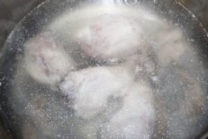 Вскипятить в подходящей кастрюле воду, затем опустить в нее части свиной голяшки и куриные кости (например, оконечные части куриных крыльев).