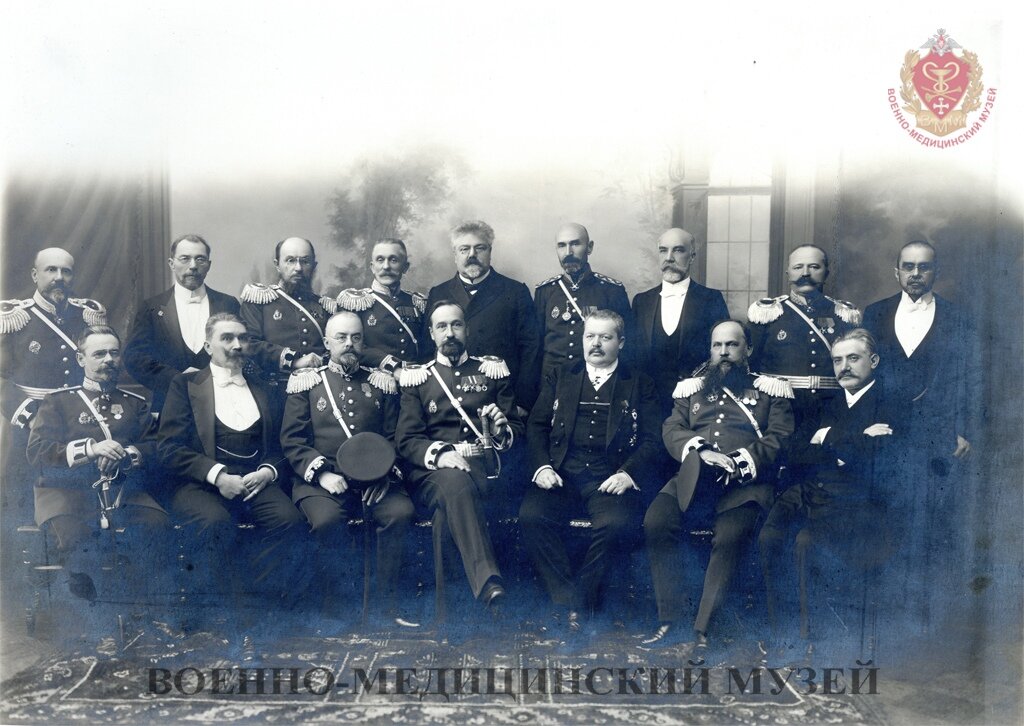 Фотография групповая профессорско-преподавательского состава кафедры кожных и венерических болезней Военно-медицинской академии. Кон. XIX – нач. XX вв. Фотография парадная. Девять человек из шестнадцати в парадной военной форме, с эполетами и наградами на груди, остальные в черных фраках и белоснежных рубашках. Третий слева в первом ряду в парадном мундире с эполетами и шпагой на ремне через правое плечо сидит профессор Т.П. Павлов. Из коллекции Военно-медицинского музея.