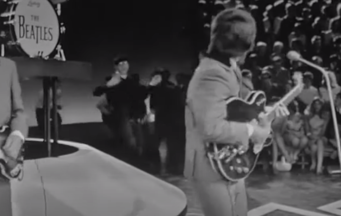 Джордж Харрисон поворачивается в сторону танцующей публики при исполнении песни.
