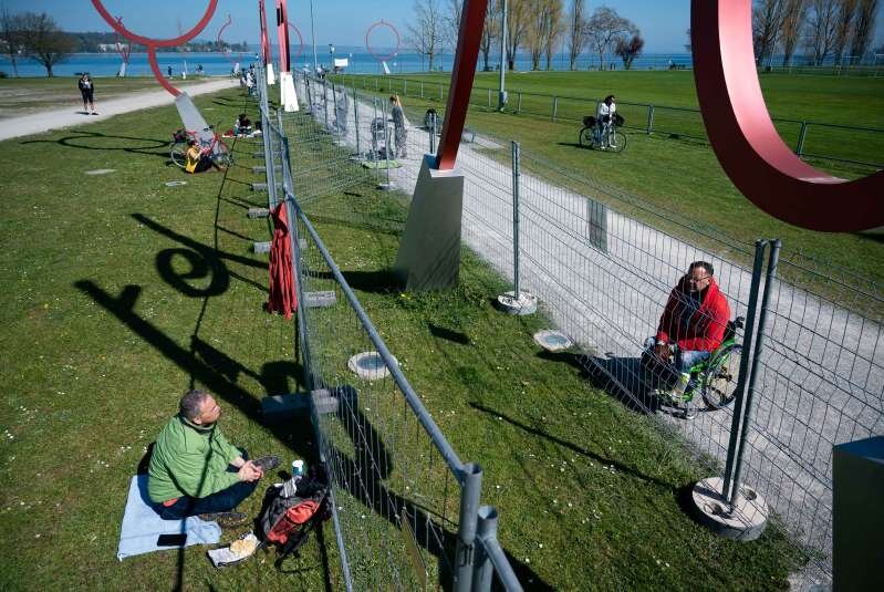 Жители Германии и Швейцарии общаются через границу, огороженную в ответ на коронавирусный кризис, 6 апреля. Getty Images