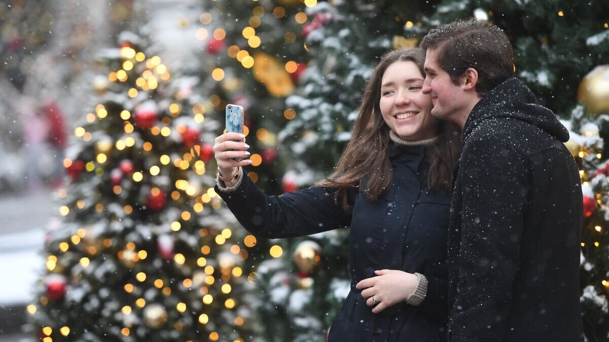    Молодые люди фотографируются во время снегопада в Москве© РИА Новости / Кирилл Каллиников