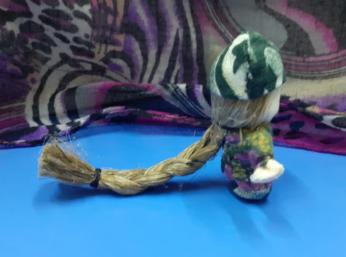 Мужская кукла Доля. Вид сбоку. Здесь хорошо видна упругая коса, которая направлена вниз к земле. Также вниз направлены ручки куклы