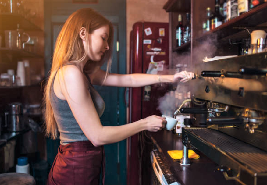 Девушка готовит молоко, регулируя подачу давления через носик панарелло