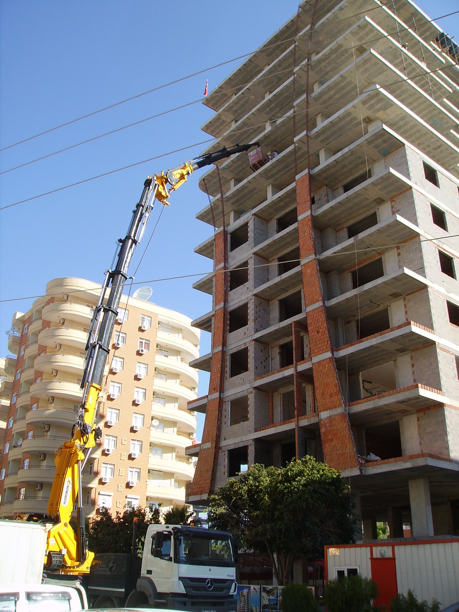 Передвижным краном подымают паллету кирпичей на 9 этаж.