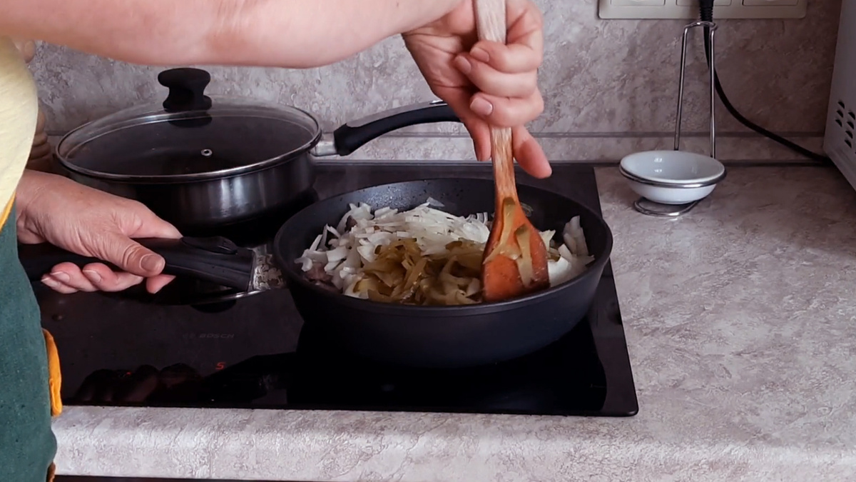 Добавим к обжаренному мясу лук и соленые огурцы.