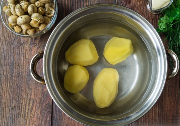 Как приготовить слоеный салат "Грибная поляна": 
Картофель вымоем и почистим, отварим клубни до готовности.