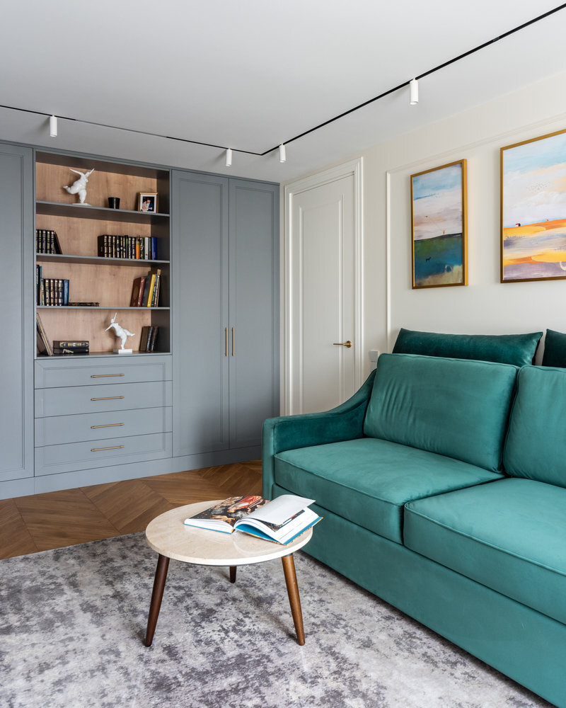 Также в гостиной нашлось место для встроенного шкафа, его изготовили по эскизам дизайнера. Несмотря на небольшую глубину — 40 см — он получился достаточно функциональным. В нём есть секция для хранения верхней одежды, открытые полки, выдвижные ящики и даже хозблок с пылесосом и гладильной доской.