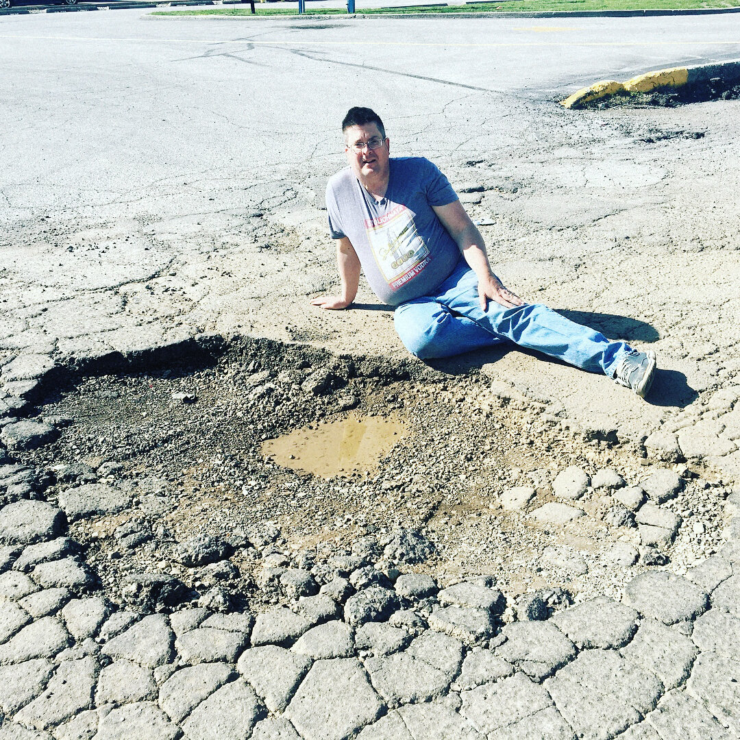 Мужчина фотографии на фоне огромной ямы.