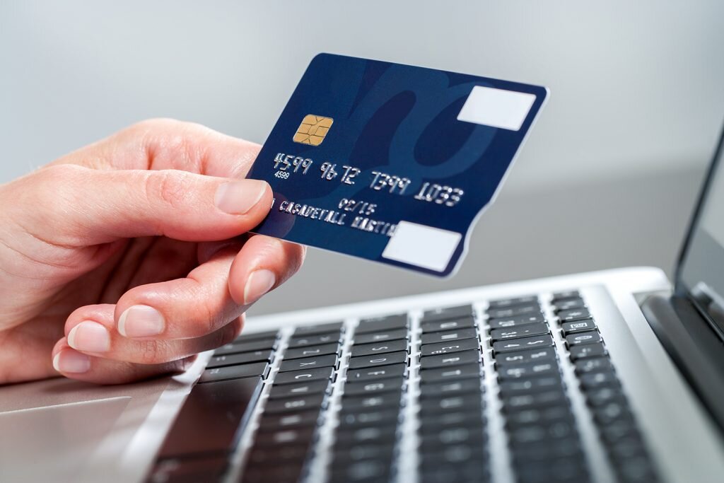    Macro close up of female hand holding credit card on laptop. admin